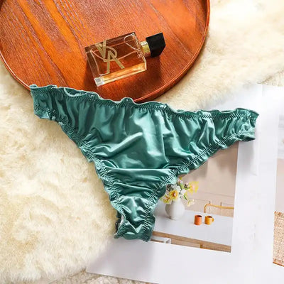 Single mint green satin thong with ruffled waistband and leg edges on fur background