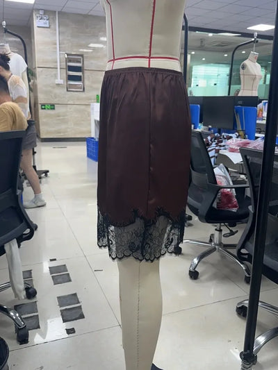 Back view of dark brown mini skirt showing full black lace hem panel on mannequin in studio setting