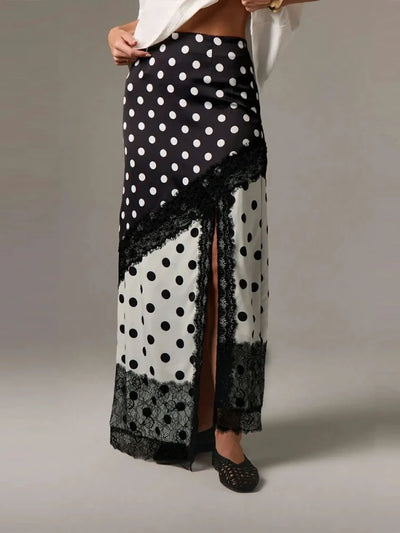 Front view of black and white polka dot satin maxi skirt with diagonal black lace panel and front slit