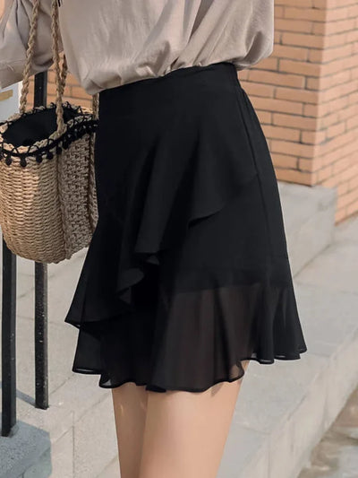 Side view of black ruffled chiffon mini skirt with fluid lower tier against brick background