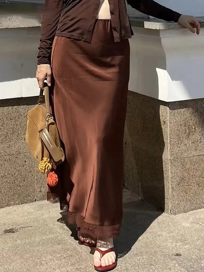 Brown satin midi skirt styled with a brown cardigan and tan suede bag, street-style shot outdoors