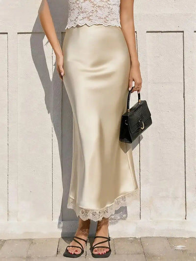 Champagne satin midi skirt with lace hem, paired with a white lace crop top and black mini bag