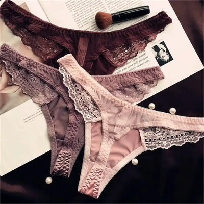 Three lace thong panties in dark burgundy, mauve, and blush pink, overlapping flat lay on magazine