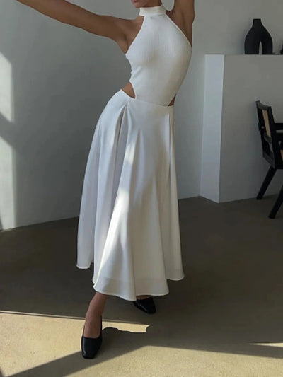 Woman in white halter crop top and ivory flared satin midi skirt arm raised indoors