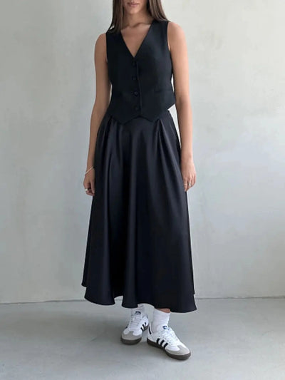 Woman wearing black vest over full black satin midi skirt with white Adidas sneakers