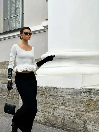 Woman in white bubble-hem long-sleeve crop top with black midi skirt, leather gloves, and Chanel bag