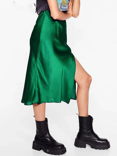 Side view of deep green satin midi skirt with visible side slit and chunky boots