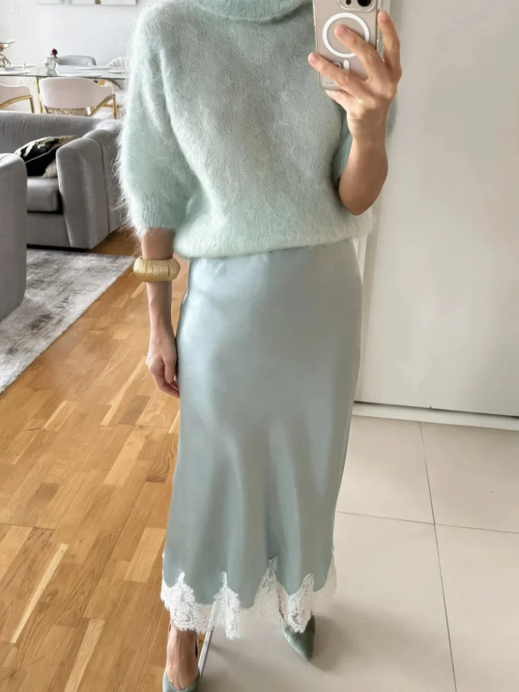 Woman wearing a mint satin midi skirt with white lace hem and matching pointed-toe heels, mirror selfie in a modern living room