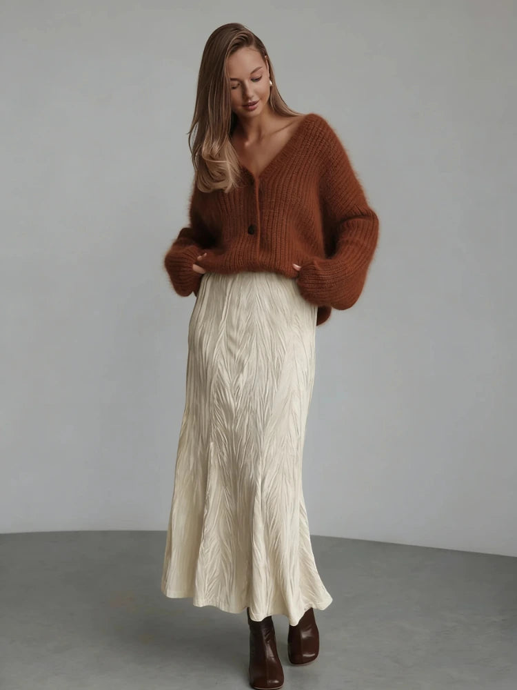 Woman wearing ivory textured midi satin skirt with rust brown fuzzy cardigan and dark ankle boots