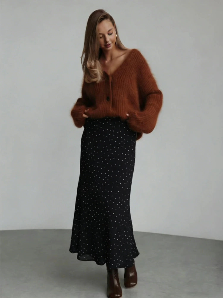 Woman wearing a black polka dot midi skirt with a rust knit and brown ankle boots
