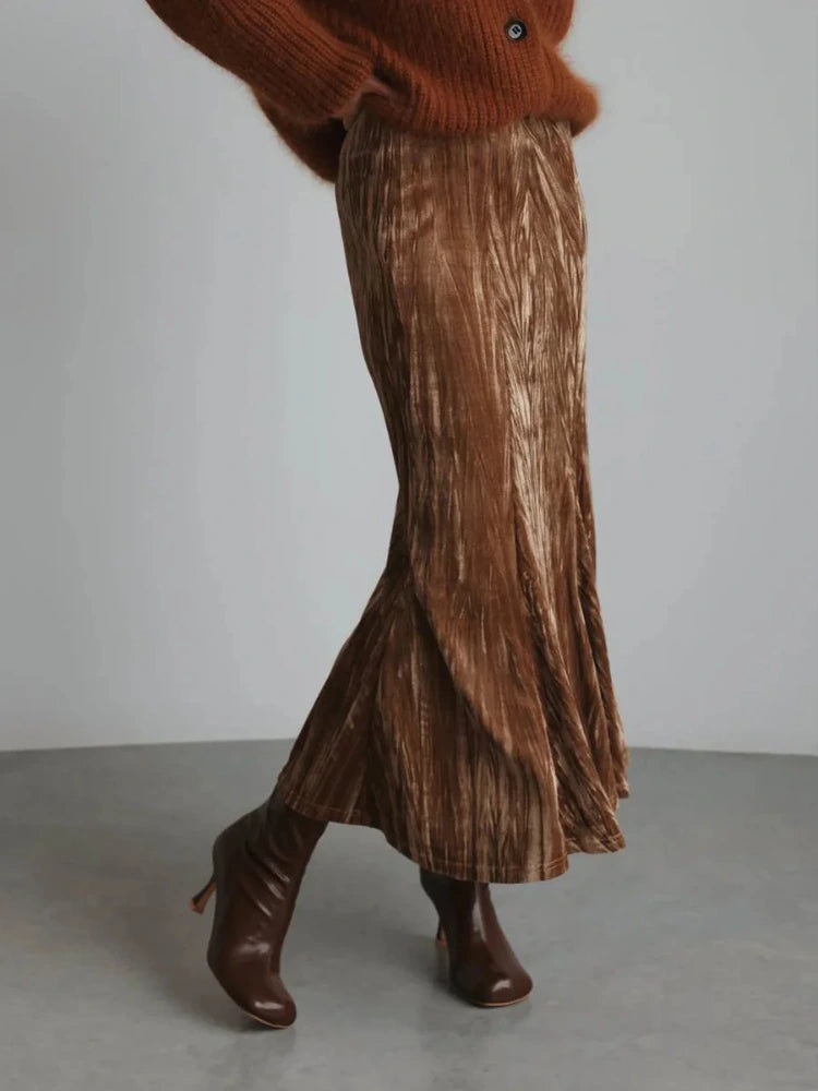 Model wearing a crinkled brown midi skirt with rust knit sweater and tall brown heeled boots