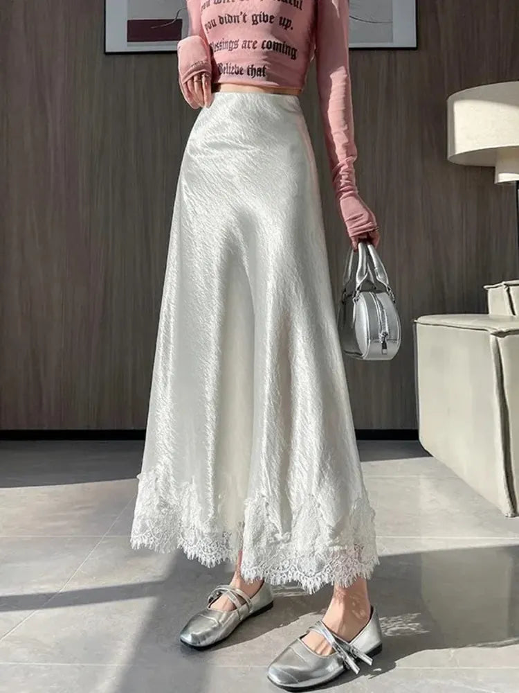 White crinkled satin A-line midi skirt with lace hem worn with pink crop top and silver shoes