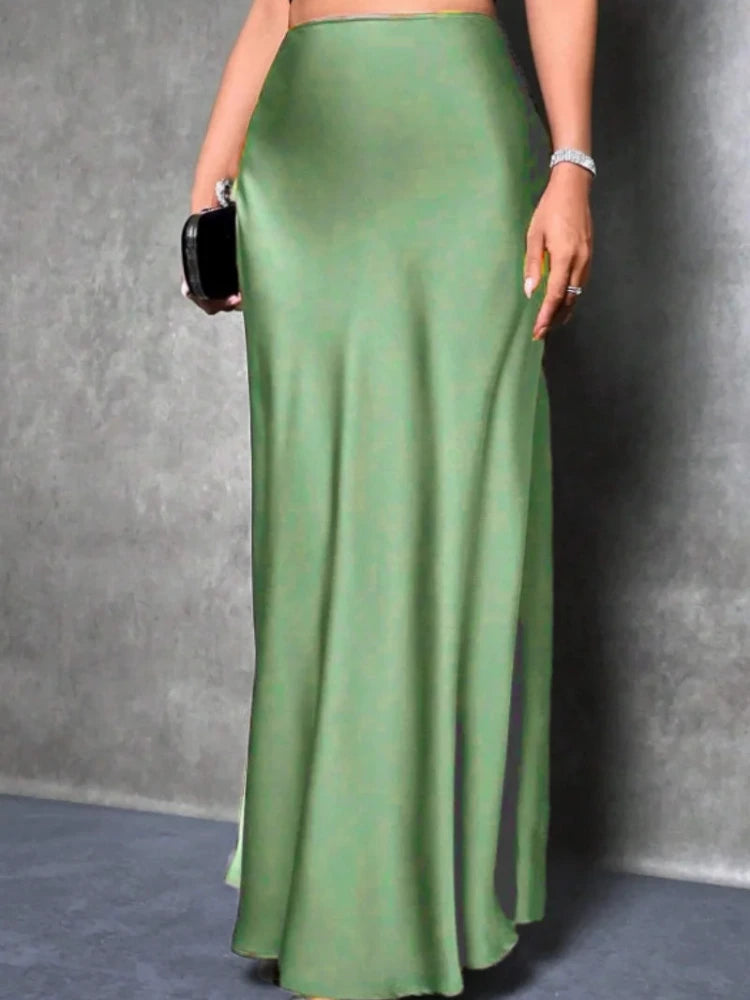 Model wearing a sage green high-waist maxi satin skirt with a floor-grazing A-line silhouette