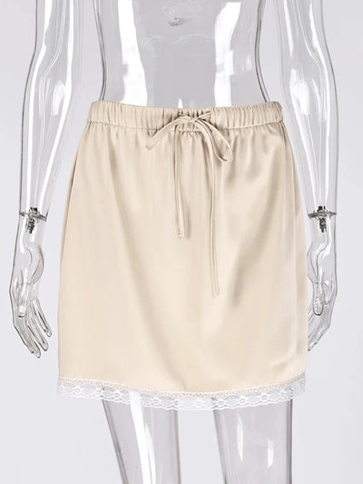 Flat lay of apricot satin mini skirt with white floral lace hem and satin ribbon drawstring on mannequin