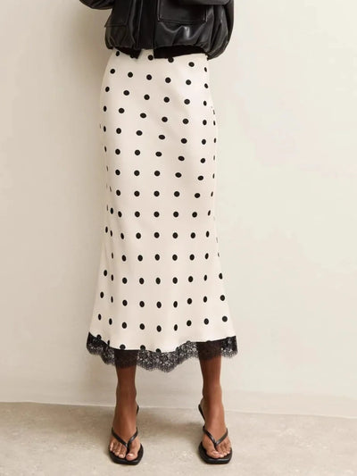 Full-length view of an ivory polka dot midi skirt with black lace hem trim, styled with flip-flops