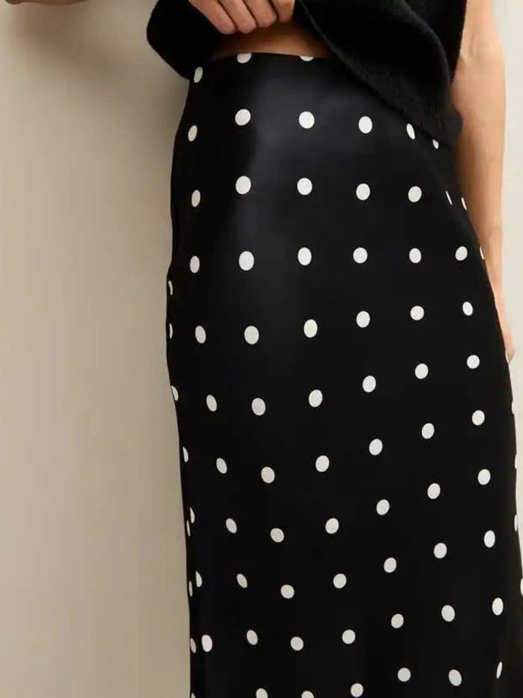 Woman wearing black polka dot midi skirt with lace hem and black knit top, front view