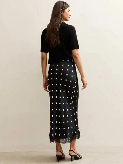 Back view of black polka dot midi skirt with lace trim hem and strappy heeled sandals