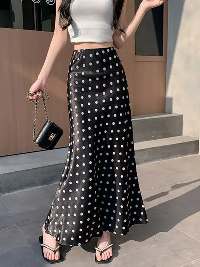 Front view of black polka dot mermaid maxi satin skirt styled with white crop top and pearl sandals