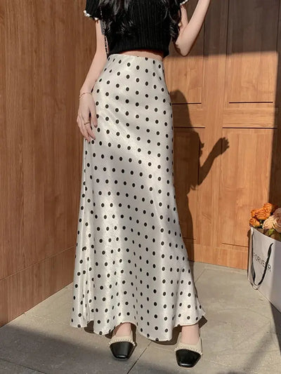 Woman standing in ivory polka dot high-waist midi skirt paired with black crop top and embellished flats