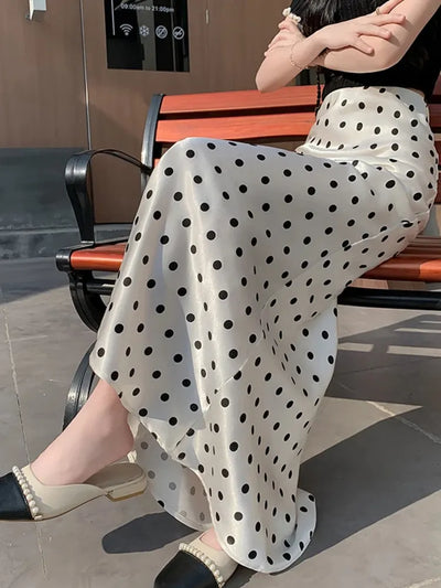 Close side view of ivory black polka dot midi skirt with flared hem, worn seated on a wooden bench outdoors
