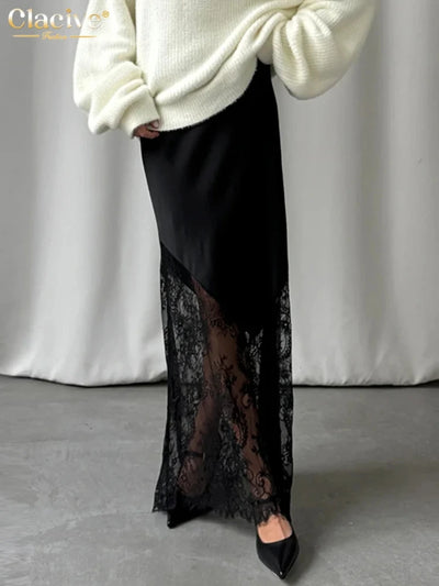 Front view of black satin and lace midi skirt showing sheer diagonal lace panel and scalloped hem edge with cream oversized sweater