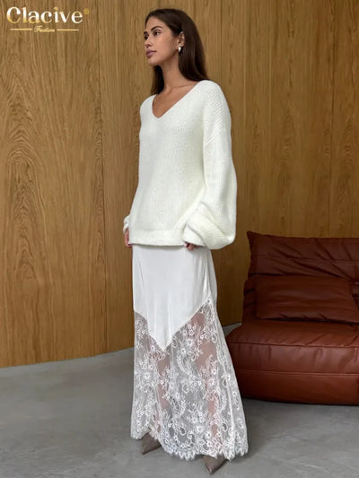 Woman wearing white fuzzy V-neck sweater over white satin and lace maxi skirt