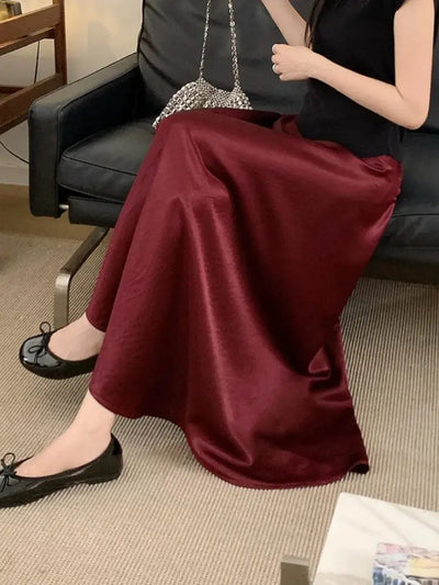 Woman seated on a sofa wearing a full flared burgundy midi skirt with black ballet flats