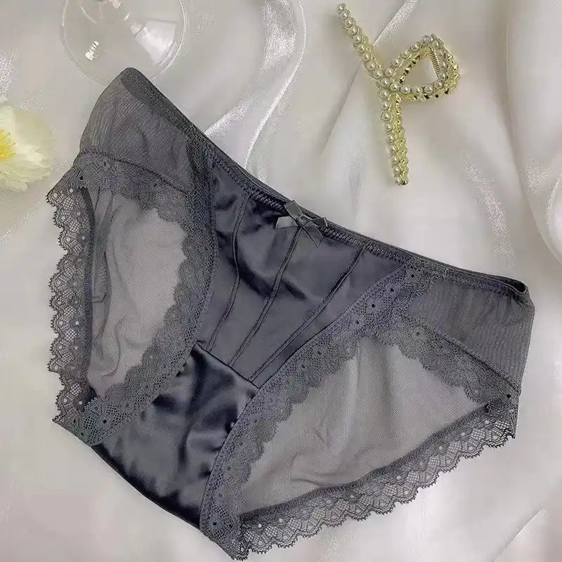Gray satin panties with scalloped lace trim, sheer mesh sides, and bow detail, flat lay on white fabric