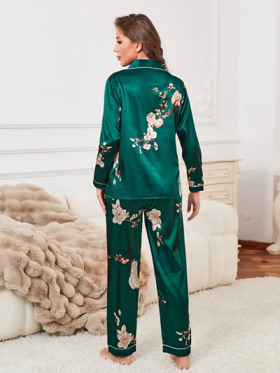 Back view of woman standing wearing green floral crane satin pajama set with white piping details