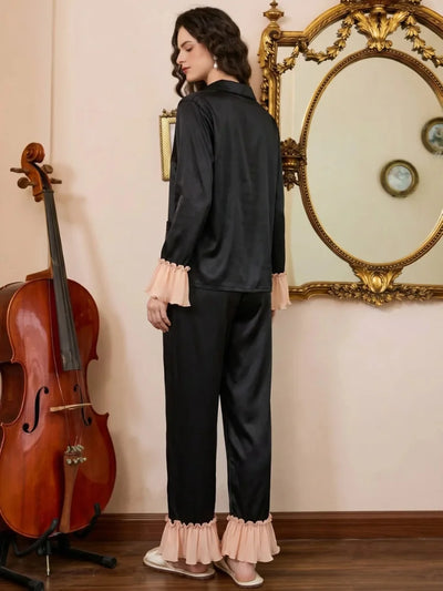 Back view of black satin pajama set showing pink pleated ruffle sleeve and hem trim