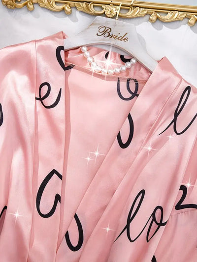 Close-up of pink satin robe collar with love print on a Bride hanger