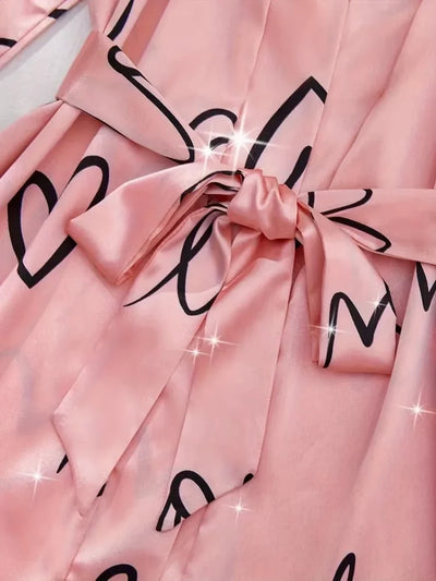 Close-up of pink satin robe waist tie sash with love print detail