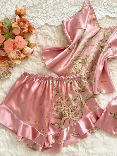 Close-up of blush pink botanical print satin cami and ruffled shorts set laid flat on white fur