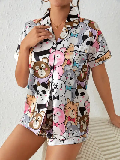 Close-up front view of pajama set showing dense cartoon animal print and black piping