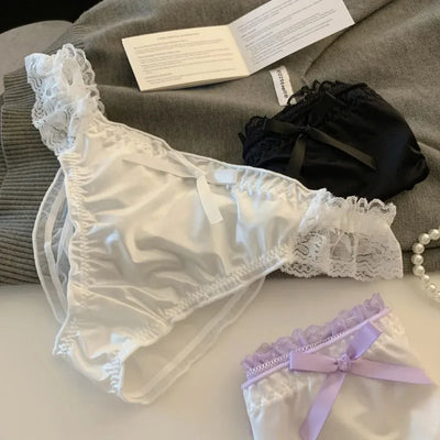 White satin panties with white lace trim and bow, lavender pair in background flat lay