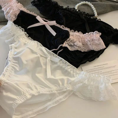 Black and white satin panties with pink lace trim and bow detail close-up flat lay