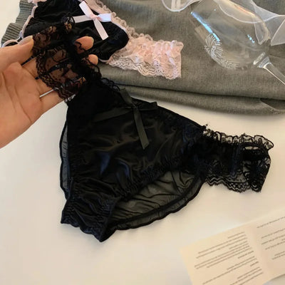 Black satin panties with black lace trim and black bow ribbon held in hand flat lay