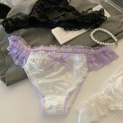 White satin panties with lavender lace trim and purple bow, black pair in background