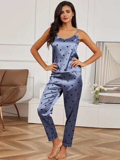 Woman in dusty blue satin heart print cami and full-length pajama pants, hands on hips