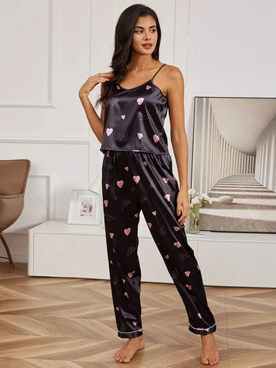 Woman wearing black satin pajama set with pink heart print cami top and long pants