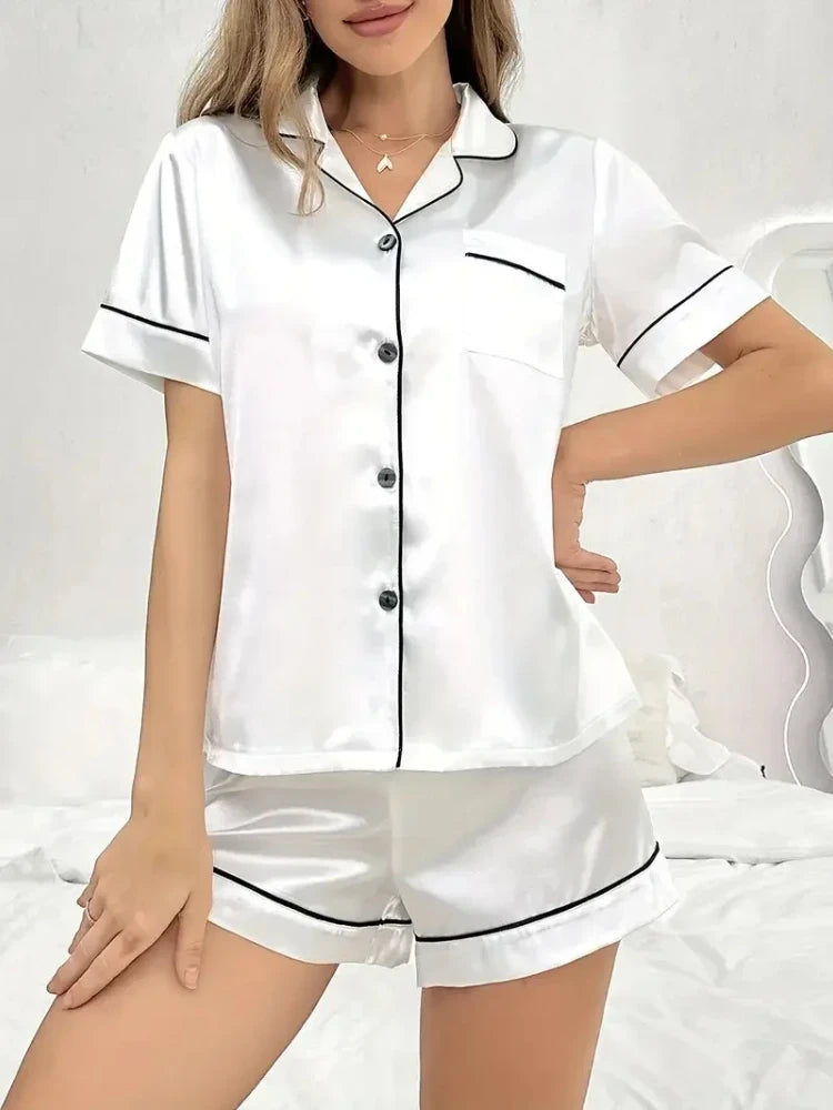 Woman wearing white satin button-down pajama set with black piping trim and matching shorts