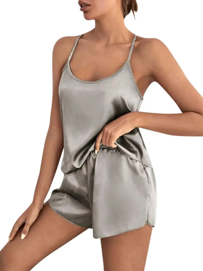 Woman wearing gray satin scoop-neck cami pajama set with matching shorts and crossback straps