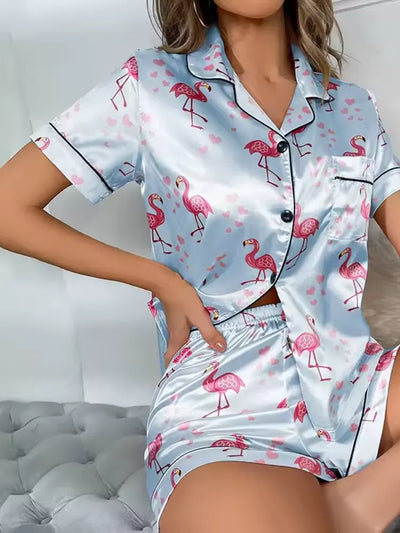Woman wearing light blue satin short-sleeve pajama set with pink flamingo and heart print