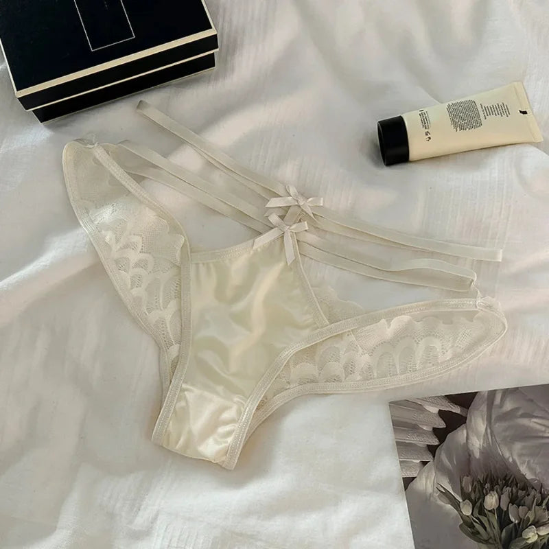 Ivory satin and scalloped lace panties with ribbon bow ties flat lay on white fabric