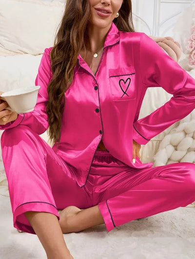 Close-up of hot pink satin pajama set with black heart embroidery on chest pocket