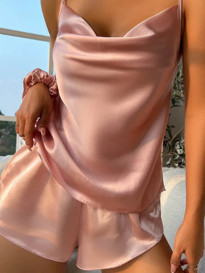 Blush satin cowl-neck cami top draped at chest with matching ruffle shorts and scrunchie on wrist