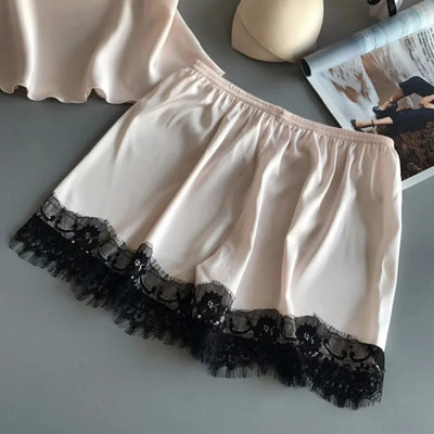 Close-up of blush satin shorts with double-layer black lace hem, elastic waistband detail