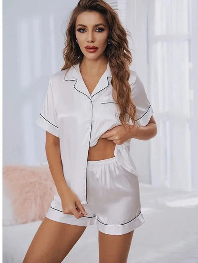 Woman wearing white satin short-sleeve pajama set with black contrast piping trim