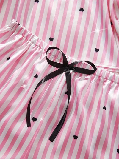 Close-up of black satin bow at the elastic waistband of pink striped pajama shorts