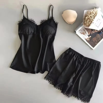 Black satin cami and shorts pajama set with lace trim, flat lay with bra insert and magazine